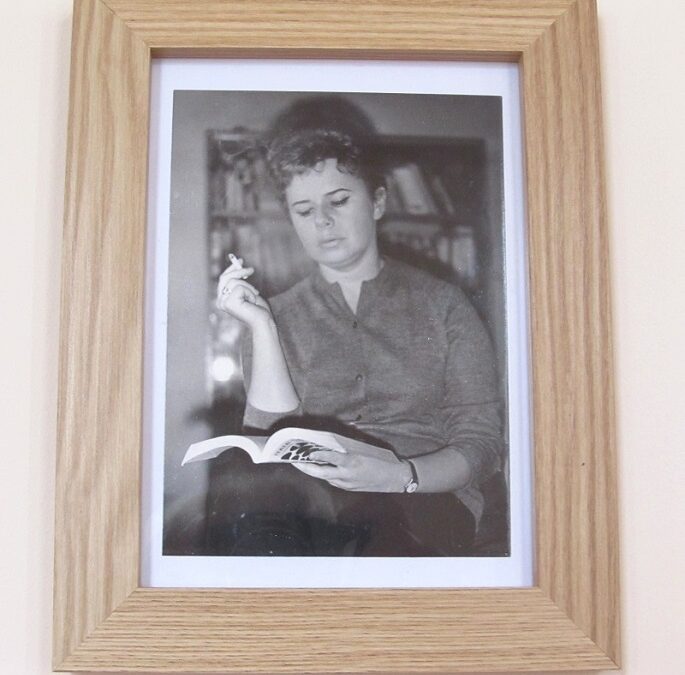 11. W ramce zdjęcie siedzącej kobiety z książką na kolanach i papierosem w ręce. Zdjęcie Anny Markowej.