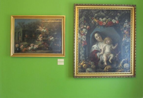 Na zielonej ścianie wiszą dwa obrazy. Z prawej Madonna z dzieciątkiem w otoczeniu kwiatów i owoców. Z lewej wnętrze domu przybranego bukietami kwiatów.